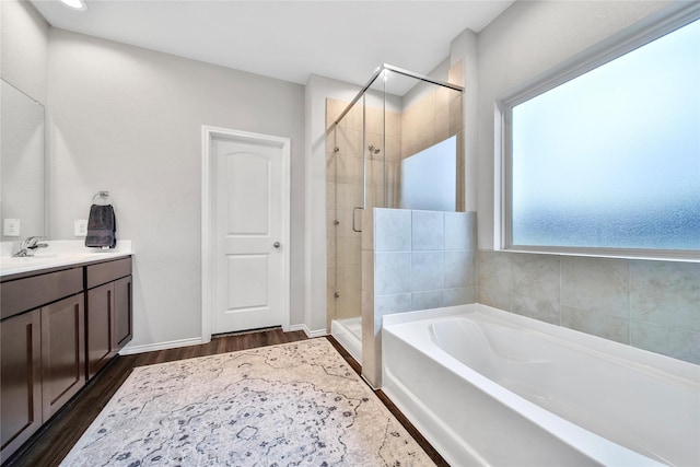 bathroom featuring vanity, wood finished floors, baseboards, a shower stall, and a garden tub