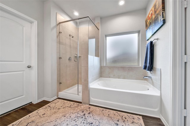 full bath with a bath, wood finished floors, a stall shower, and baseboards