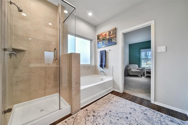 full bath featuring a bath, wood finished floors, a stall shower, and baseboards