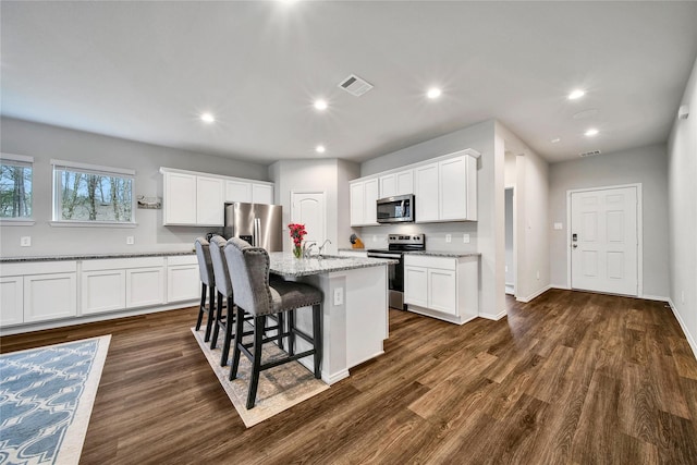 kitchen featuring visible vents, dark wood-type flooring, recessed lighting, appliances with stainless steel finishes, and a kitchen breakfast bar