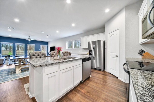 kitchen with visible vents, a sink, open floor plan, dark wood finished floors, and stainless steel appliances