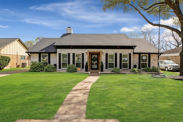 view of front facade featuring brick siding, a chimney, a front lawn, and roof with shingles