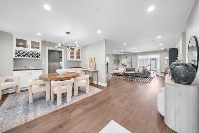 dining area featuring wood finished floors, recessed lighting, a dry bar, baseboards, and a chandelier