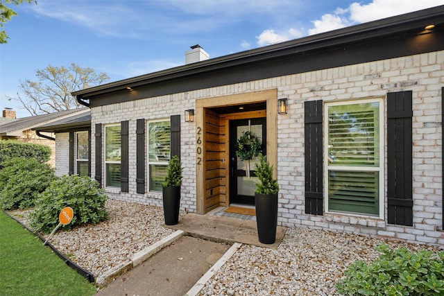 entrance to property with brick siding and a chimney