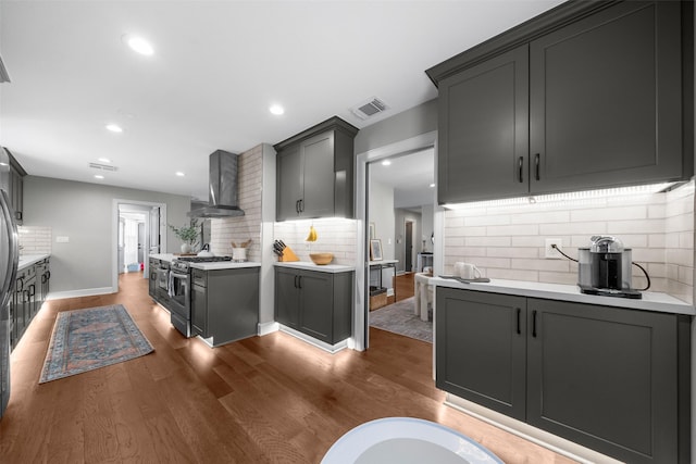 kitchen featuring visible vents, light countertops, dark wood-style floors, stainless steel gas stove, and wall chimney exhaust hood