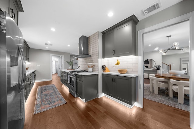 kitchen with visible vents, stainless steel appliances, light countertops, and wall chimney range hood