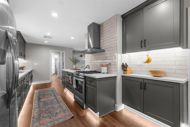 kitchen featuring visible vents, dark wood-type flooring, light countertops, stainless steel appliances, and wall chimney exhaust hood