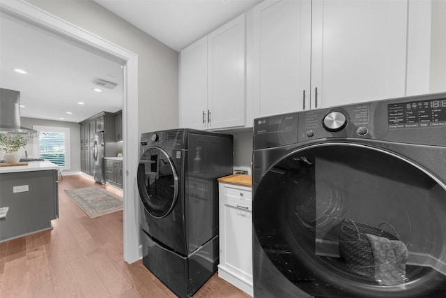 washroom with light wood-style flooring, washer and clothes dryer, a sink, recessed lighting, and cabinet space