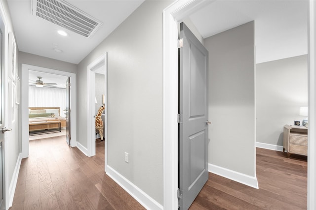 corridor with visible vents, baseboards, and dark wood finished floors