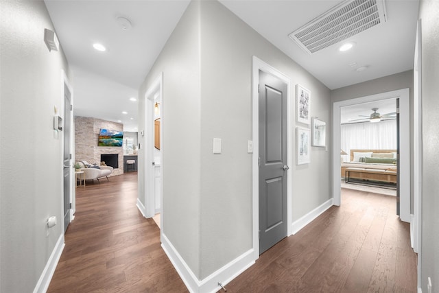 hallway with visible vents, baseboards, and wood finished floors