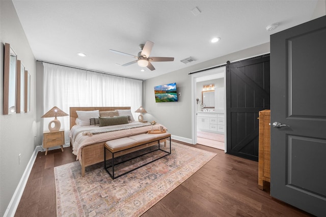 bedroom featuring a barn door, baseboards, visible vents, and dark wood-style floors