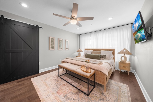 bedroom featuring recessed lighting, baseboards, a barn door, and dark wood-style flooring