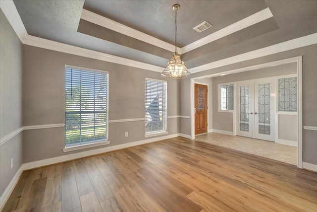 unfurnished room featuring visible vents, a notable chandelier, wood finished floors, baseboards, and a raised ceiling