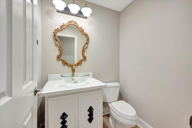 half bath featuring toilet, vanity, and baseboards