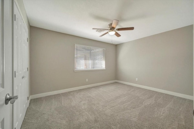 spare room with visible vents, light colored carpet, baseboards, and ceiling fan