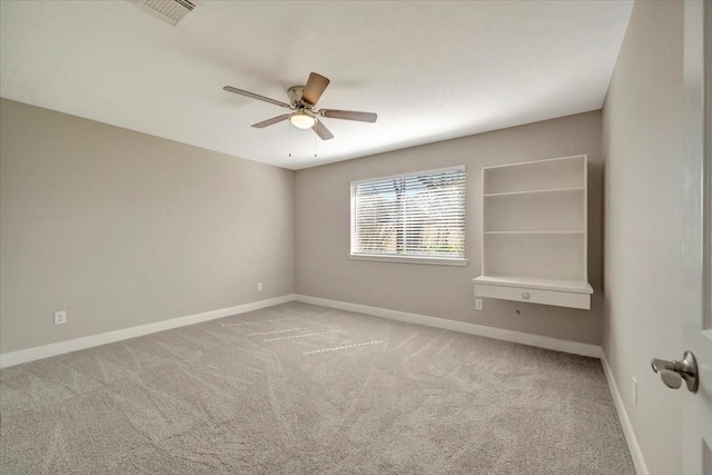 carpeted spare room featuring visible vents, baseboards, and ceiling fan