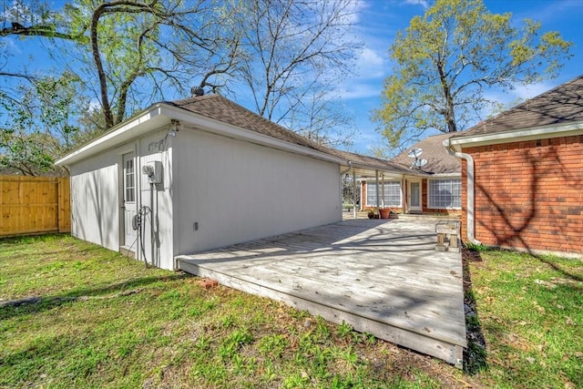 exterior space featuring fence, a lawn, and a shingled roof