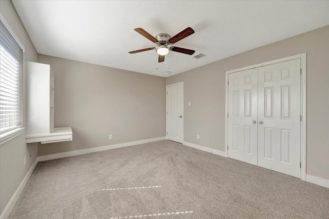 unfurnished bedroom with visible vents, a closet, carpet flooring, baseboards, and ceiling fan