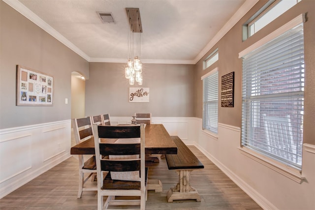 dining space with arched walkways, visible vents, ornamental molding, and wood finished floors