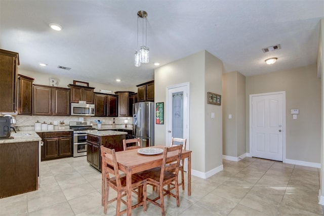 kitchen featuring backsplash, stainless steel appliances, dark brown cabinetry, and visible vents