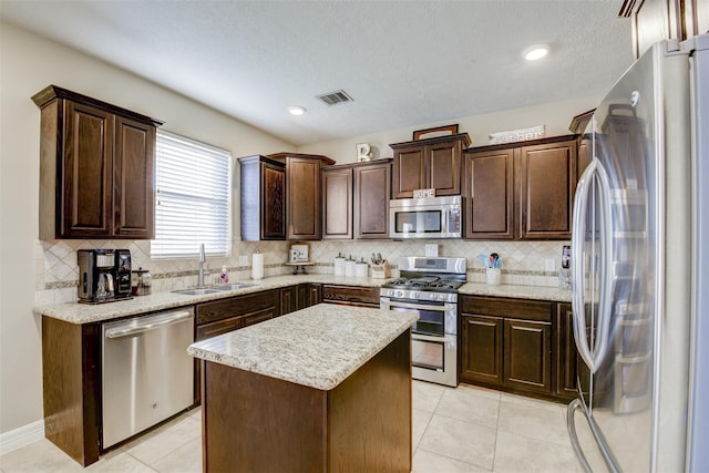 kitchen featuring visible vents, a sink, dark brown cabinetry, appliances with stainless steel finishes, and a center island