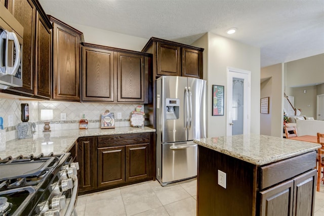 kitchen featuring light stone counters, stainless steel appliances, and decorative backsplash