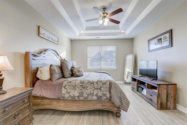 bedroom with crown molding, baseboards, light wood-style floors, and a tray ceiling