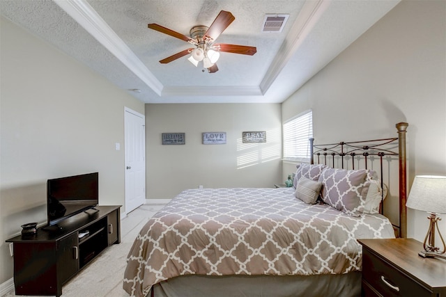 bedroom featuring a ceiling fan, baseboards, visible vents, a textured ceiling, and a raised ceiling