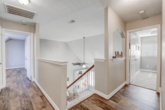 hallway featuring an upstairs landing, visible vents, and hardwood / wood-style flooring