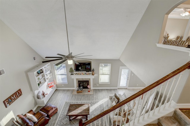 living room with a wealth of natural light, wood finished floors, ceiling fan, and a fireplace