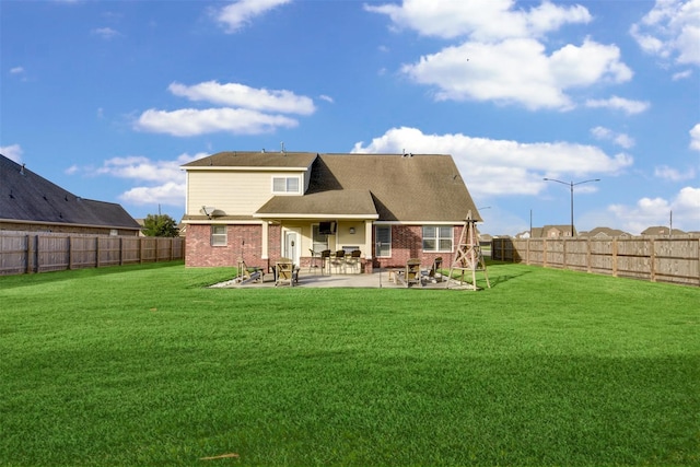 rear view of property with a yard, a patio area, brick siding, and a fenced backyard