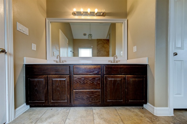 full bathroom with double vanity, a sink, and baseboards