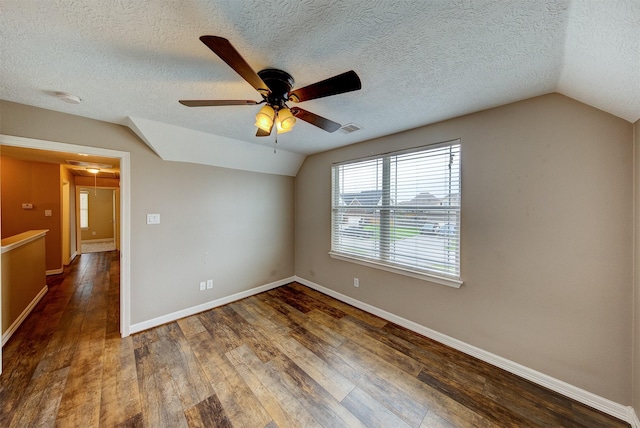 empty room featuring vaulted ceiling, baseboards, visible vents, a ceiling fan, and wood finished floors