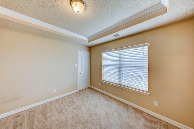 spare room with a raised ceiling, ornamental molding, a textured ceiling, and visible vents