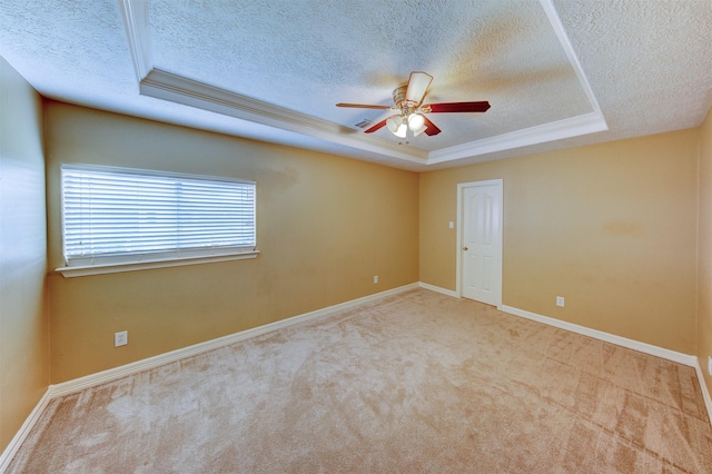 empty room with carpet flooring, baseboards, a textured ceiling, a raised ceiling, and a ceiling fan
