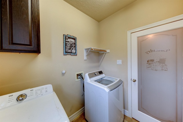 washroom featuring baseboards, cabinet space, a textured ceiling, and washer and clothes dryer