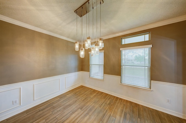 unfurnished dining area with wainscoting, a textured ceiling, a chandelier, and wood finished floors
