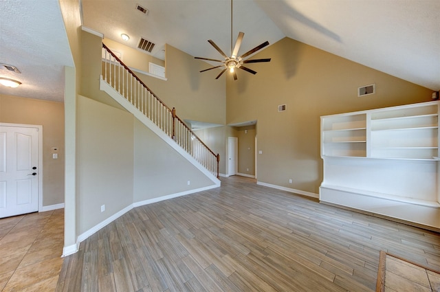 unfurnished living room featuring a ceiling fan, stairs, and visible vents