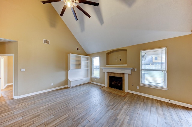 unfurnished living room featuring baseboards, light wood-style floors, ceiling fan, a tiled fireplace, and visible vents