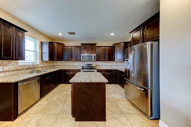 kitchen with a sink, appliances with stainless steel finishes, a center island, visible vents, and dark brown cabinets