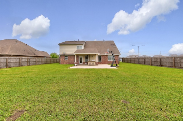 back of property with a fenced backyard, brick siding, a lawn, and a patio area