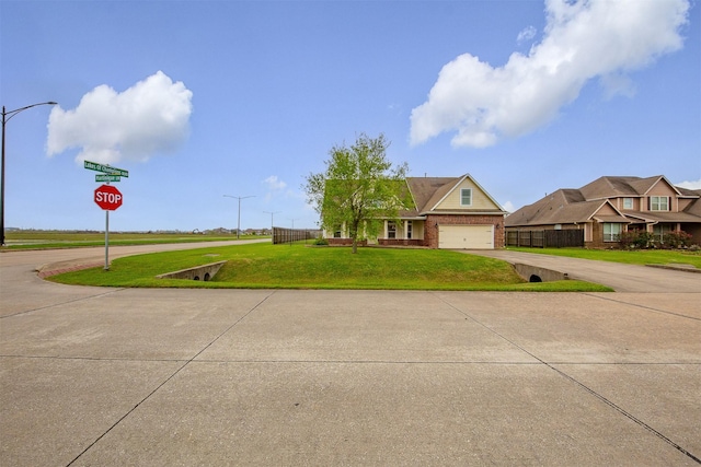view of front of property featuring curved driveway, a garage, fence, and a front lawn