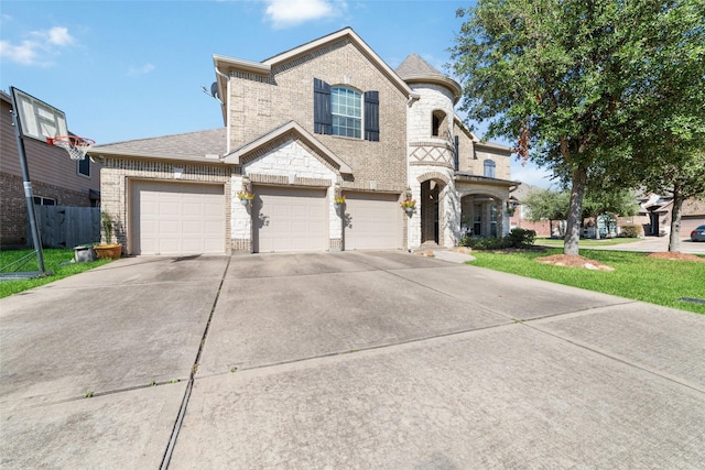 french country inspired facade featuring an attached garage, concrete driveway, a front lawn, stone siding, and brick siding