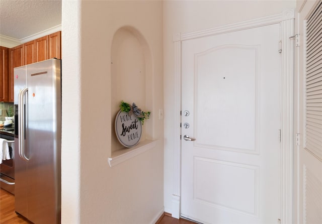 entryway with light wood-type flooring and a textured ceiling