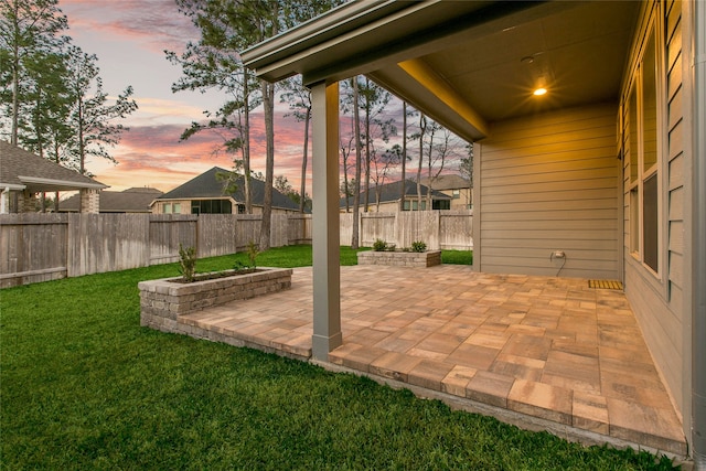 patio terrace at dusk with a yard and a fenced backyard