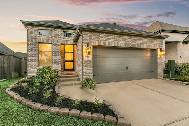 view of front of home featuring concrete driveway, fence, brick siding, and a garage