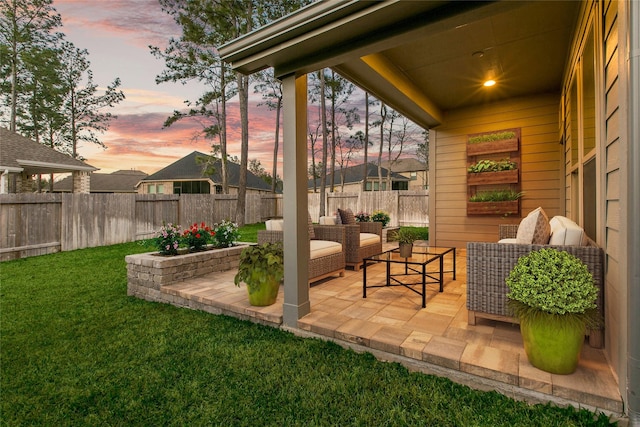 patio terrace at dusk featuring outdoor lounge area, fence private yard, and a lawn