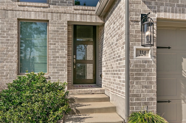 view of exterior entry with a garage and brick siding