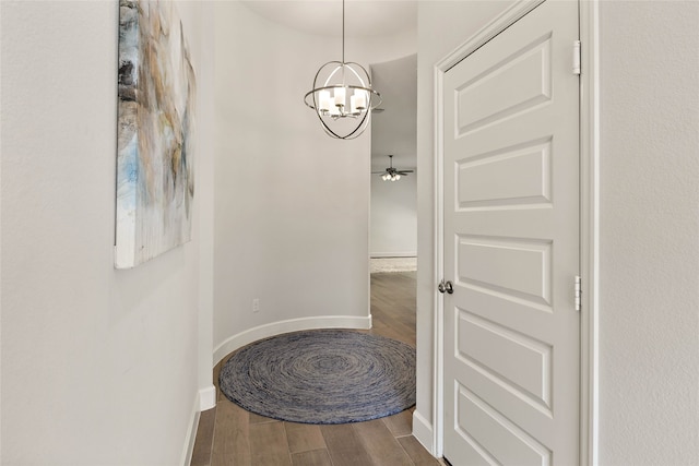 corridor featuring a chandelier, baseboards, and wood finished floors