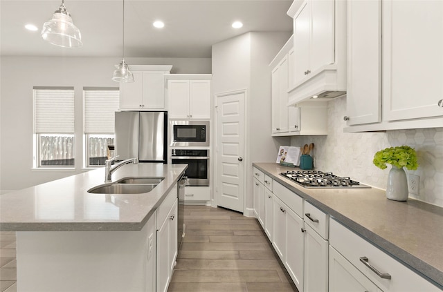 kitchen featuring wood finished floors, a sink, white cabinets, appliances with stainless steel finishes, and tasteful backsplash